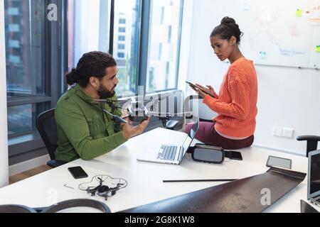 Two diverse creative colleagues sitting at desk talking Stock Photo