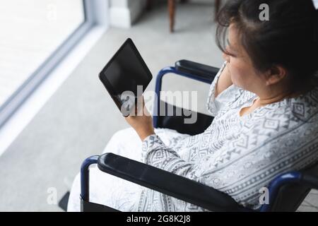 Happy senior asian woman at home using tablet Stock Photo