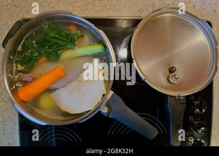Cooking chicken broth in an old pressure cooking from above Stock Photo