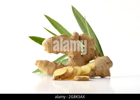 Ginger root with sliced portions and leaves behind with white isolated background reflected on white table Stock Photo