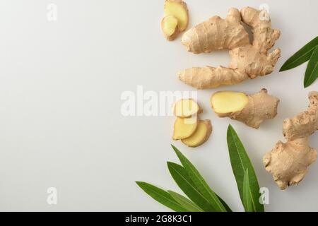 Ginger root with sliced portions and leaves on white table. Top view. Stock Photo