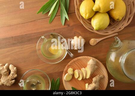 Ginger infusion on wooden table with sliced ginger root and teapot. Top view. Stock Photo