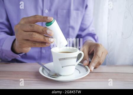 young man putting artificial sweetener in tea, Stock Photo