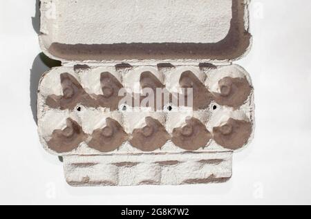 Grey egg carton without eggs on white background. egg carton box made from recycled paper with abstract repeated design pattern Stock Photo