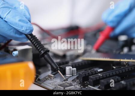 Master in gloves with equipment is testing computer motherboard Stock Photo