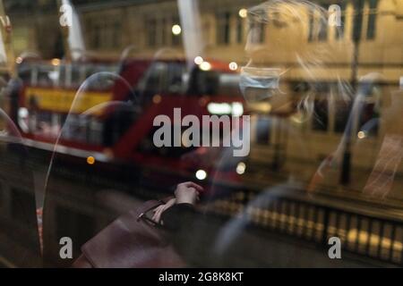 Blonde girl wearing face mask reflected in bus window at night, London, 21 February 2021 Stock Photo