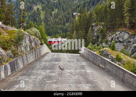 View over spillway towards construction site with car passing on provisional bridge - Sufnersee dam, Sufers, Switzerland. Stock Photo