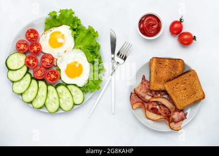 Fried chicken eggs with bacon and vegetables on a gray table. Breakfast concept. Overhead view. Flat lay composition. Food background in morning. Fres Stock Photo