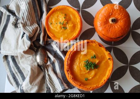 Curried butternut squash soup with coconut milk. Vegan pumpkin soup served in a squash shell. Eating healthy concept. Stock Photo