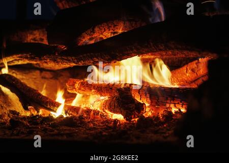 Wood in a fire with an open fire and red coals in the dark Stock Photo