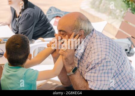 older Caucasian man playing with a disabled child in a wheelchair caressing with his hands concept of family affection Stock Photo