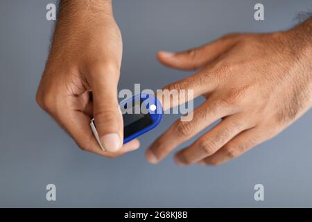 Unrecognizable man using pulse oximeter, grey background Stock Photo