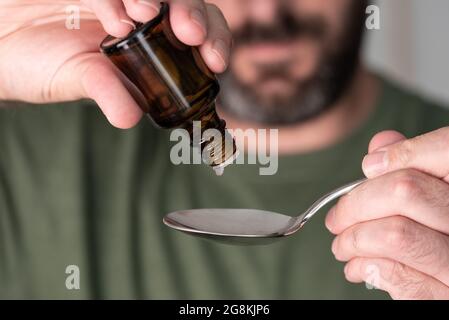 close-up of person dripping liquid medication drops onto spoon Stock Photo