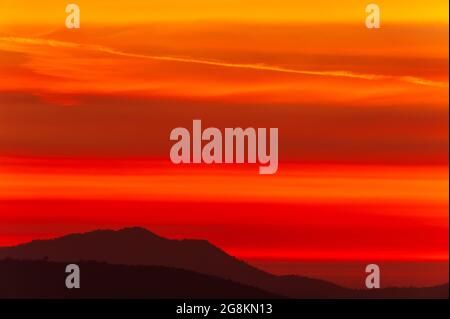 Dramatic clouds on the sunset sky over mountains, magical ripples clouds on the red sky. Focus on the sky. Stock Photo