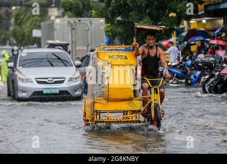 Manila, Philippines. 21st July, 2021. A man cycles through the flood brought by heavy monsoon rains in Manila, the Philippines, July 21, 2021. Credit: Rouelle Umali/Xinhua/Alamy Live News Stock Photo