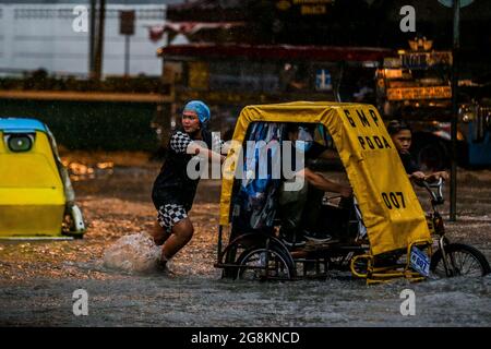 Manila, Philippines. 21st July, 2021. People wade through the flood brought by heavy monsoon rains in Manila, the Philippines, July 21, 2021. Credit: Rouelle Umali/Xinhua/Alamy Live News Stock Photo