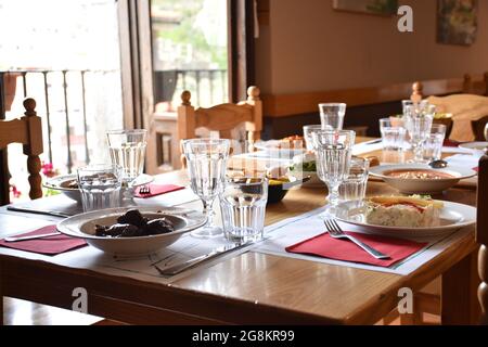 Restaurant table with plates full of food in rural area restaurant. Everything ready to eat and with lots of light coming through the window. Stock Photo