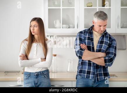 Offended mature married couple standing in kitchen with crossed arms after quarrel at home Stock Photo