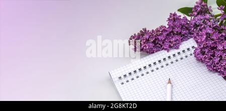 Notepad with pen and flowers. Spiral notebook and pen. Notebook lilacs on light background. Stock Photo