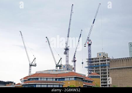 Construction cranes on a building site rising above a roof on buildings next to the Tate Modern Art Gallery in South London England UK   KATHY DEWITT Stock Photo