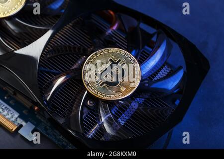Video card with a gold coin Bitcoin on the cooler close-up. The concept of mining and mining of cryptocurrency, the device of a cryptocurrency farm. Stock Photo