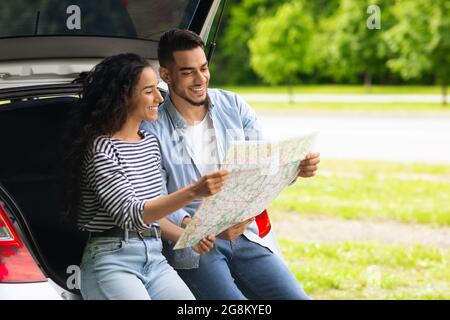 Loving middle-eastern couple watching map while having break, copy space Stock Photo