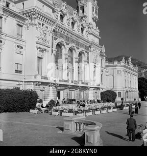 1950s, historical, at the rear of the Casino de Monte Carlo in the Principality of Monaco, people sitting outside in an area whch looks out to the sea. The grand, ornate casino building was designed by Charles Garnier, the architect who also created the majestic Paris Opera house. Built in 1863 in the Principality of Monaco, overlooking the Mediterranean, the casino is also home to the Monte-Carlo opera. Stock Photo