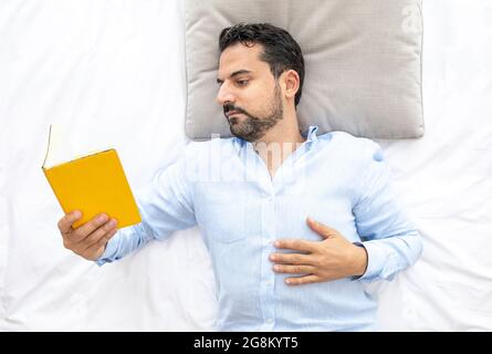 Middle aged arab man reading in bed Stock Photo