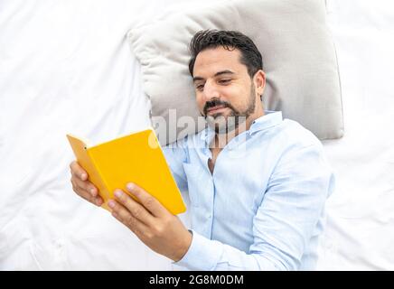 Middle aged arab man reading in bed Stock Photo