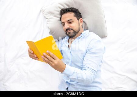 Middle aged arab man reading in bed Stock Photo