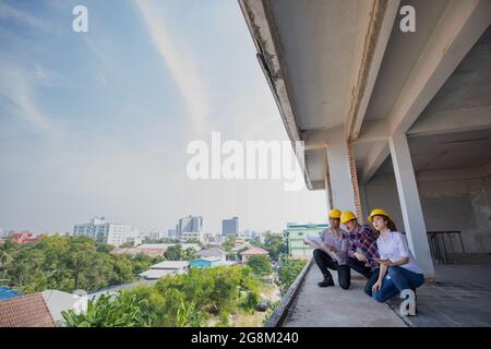 Three of diverse group of engineer team working together in costruction site with blue sky in background. Stock Photo