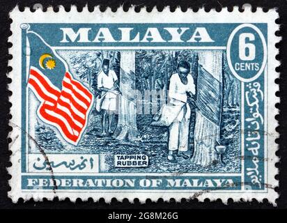 MALAYA - CIRCA 1957: a stamp printed in Malaya shows rubber tapping, is the process by which latex is collected from rubber tree, circa 1957 Stock Photo