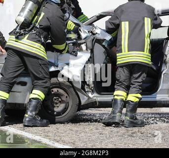 Firefighters with apparatus breathing during the rescue after the crash and the damaged car Stock Photo