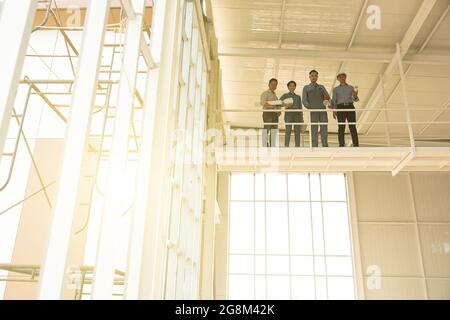 Group of engineers, man and woman, working together in construction site, standing on bridge among the scarfold. Stock Photo