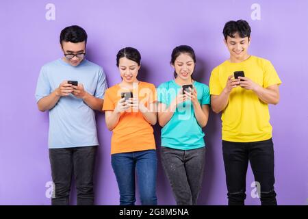 Group of young Vietnamese people using their smartphones on purple background Stock Photo
