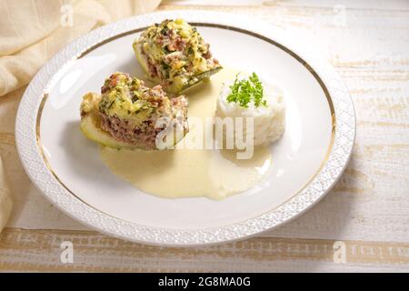 Baked courgette or zucchini slices stuffed with minced beef, bacon and cream with rice and lemon sauce on a white plate, selected focus, narrow depth Stock Photo