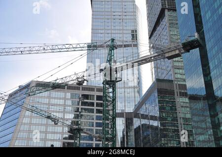 Silhouettes of tower cranes against the background of modern skyscrapers. Stock Photo