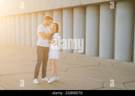 Full length shot portrait of romantic young couple in love embracing while man touching neck of girlfriends with hand. Stock Photo