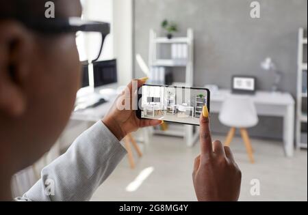 Woman holding mobile phone and taking photo of interior in office or apartment for rent