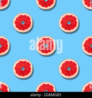 Seamless pattern with grapefruit on a blue background. Grapefruit slices seamless texture for design. Summer background. Fruit pattern. Stock Photo