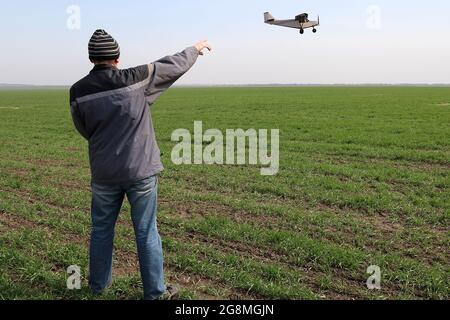 A farmer standing on his wheat field and points at a small airplane flying overhead. Stock Photo