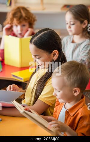 multiethnic kids reading books in classroom on blurred background Stock Photo