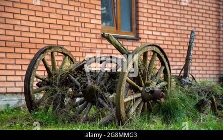 Old broken wooden cart with broken wooden wheels. Three wheels Stock Photo