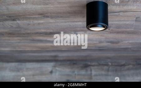 black LED lamp, on a wooden ceiling, interior design decorative lighting. Ceiling spotlights Stock Photo