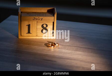 July 18 on wooden blocks. on the background of wedding rings. Holiday, wooden calendar, days and months of the year. Stock Photo