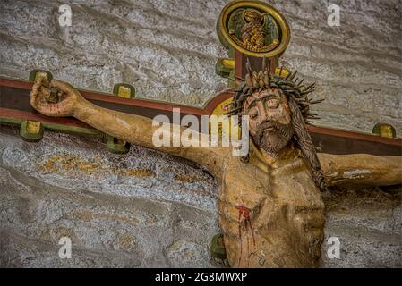 Jesus with the crown of thorns and a nail through the hand, an old colored crucifix from the 15th century with peeled painting, Borrie church, Sweden, Stock Photo
