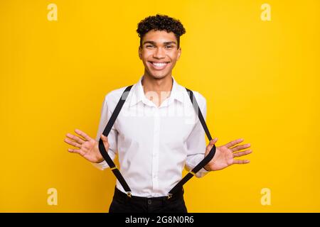 Photo of crazy funny guy look camera toothy smile wear white shirt suspenders isolated yellow color background Stock Photo