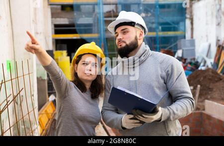 Engineers discussing blueprint at construction site Stock Photo