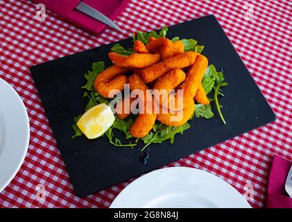 Sepia in a batter of tempera flour with lemon and arugula Stock Photo ...