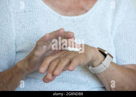 Senior women apply hand cream on her hands. Close up. Seniors everyday routine. Stock Photo